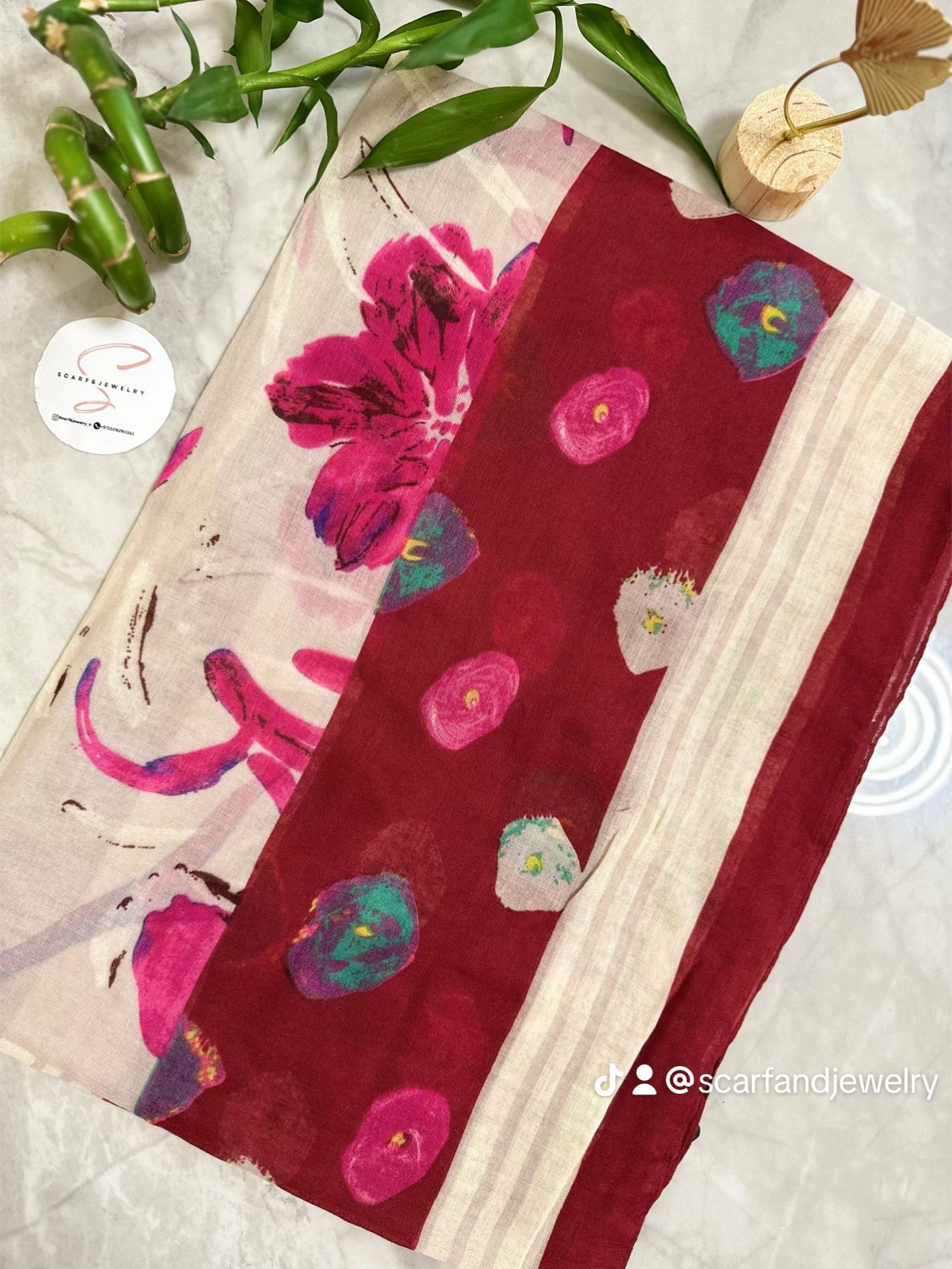 Floral-patterned fabric with pink and blue flowers on a red background, displayed on a white surface.